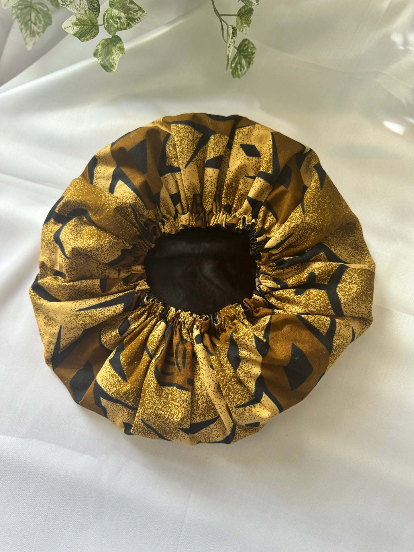 Gold and black patterned shower cap on a white background