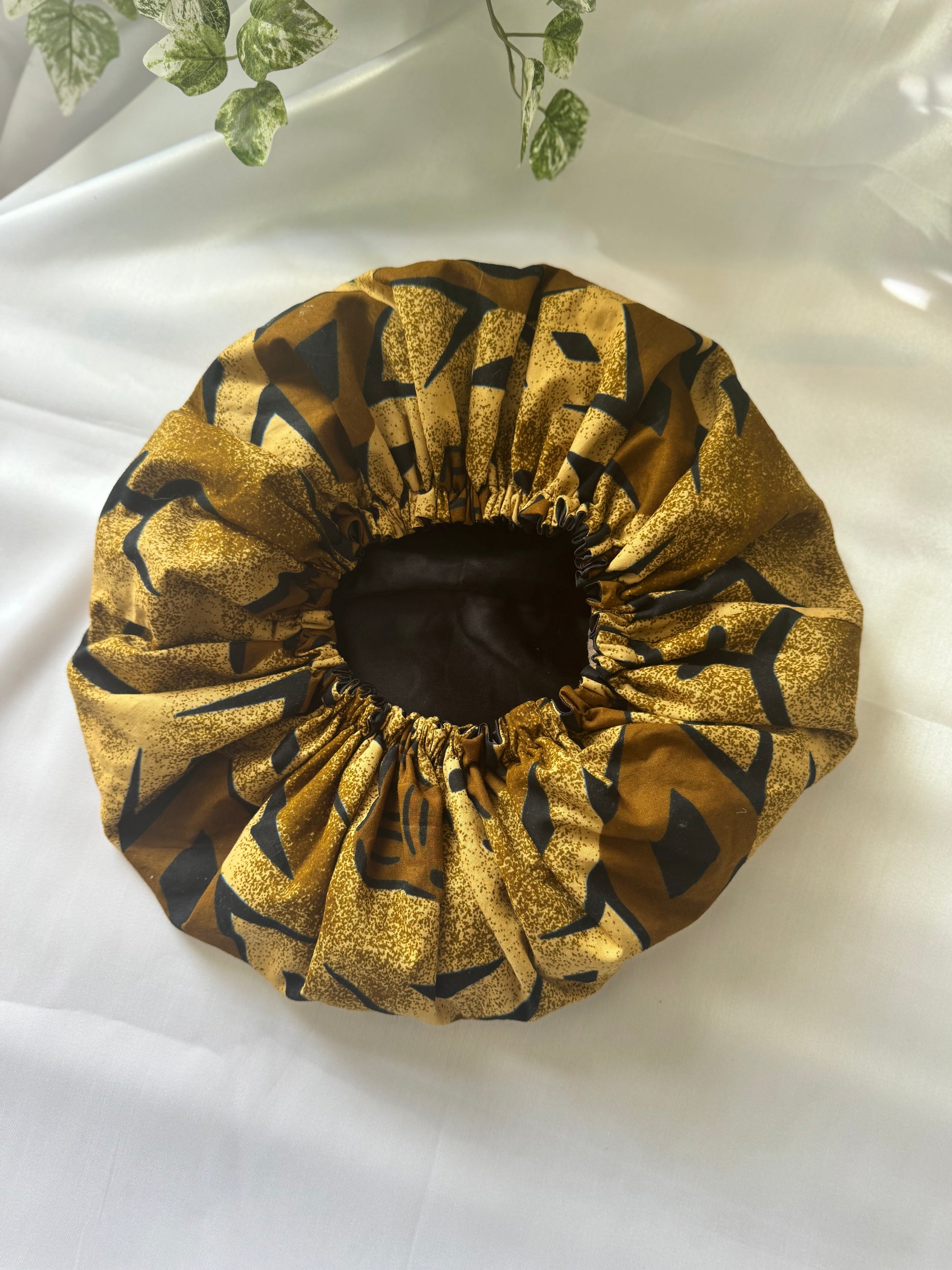 Gold and black patterned shower cap on a white background