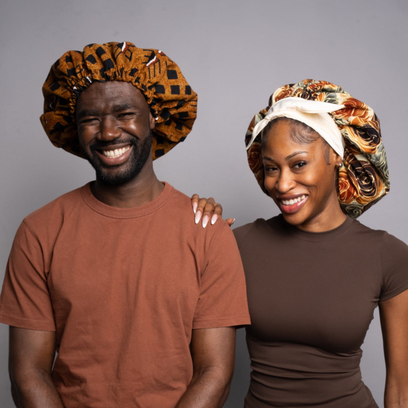 Two people wearing colourful hair bonnets 